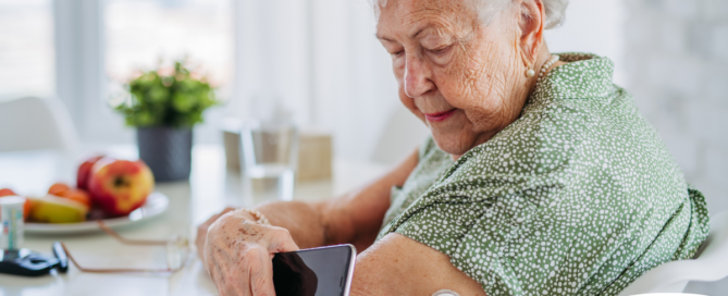 A senior woman uses her smartphone to check her glucose monitor, a tool that can be extremely helpful for diabetes care.