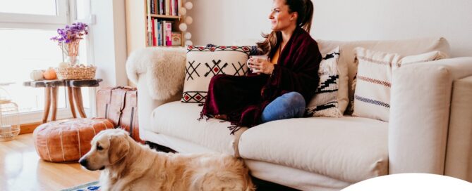 A woman relaxes with her dog while sipping on tea, representing how self-care can combat caregiver stress.