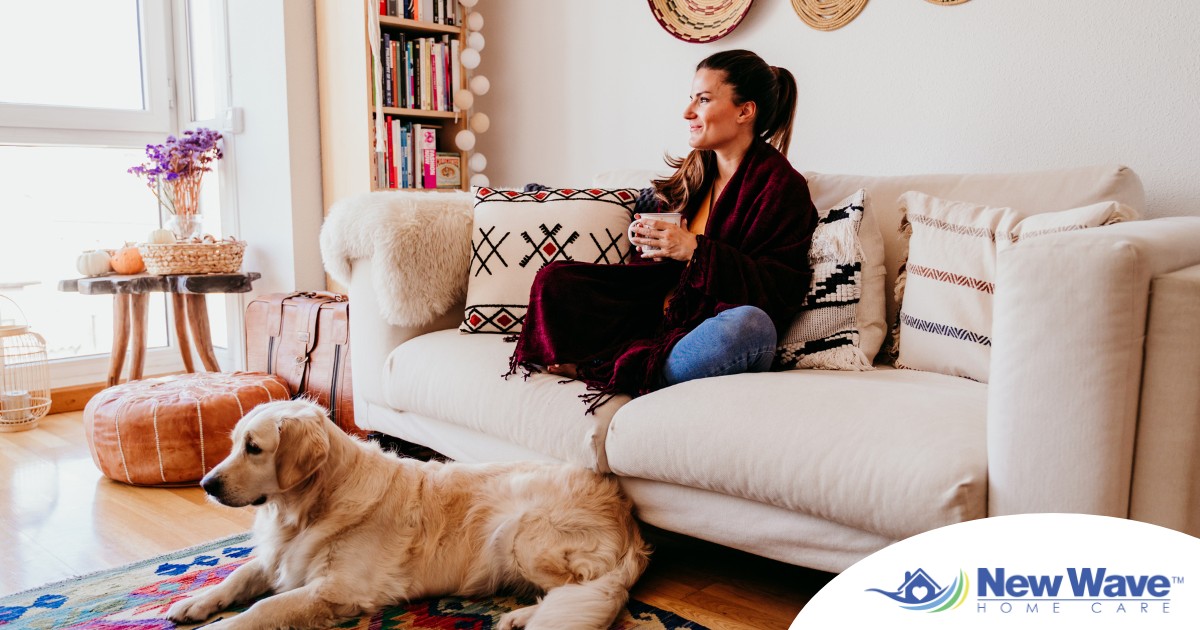 A woman relaxes with her dog while sipping on tea, representing how self-care can combat caregiver stress.