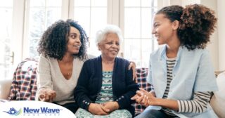 A caregiver talks with a client and her daughter, representing the type of communication that is vital when taking on a person-centered care approach.