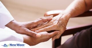 A pair of younger hands hold older ones, representing the compassionate care that a professional caregiver can provide.