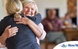 An older woman smiles as a younger woman visits her and hugs her, showing the effect that acts of kindness can have on senior loved ones.